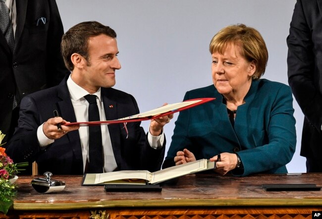 German chancellor Angela Merkel and French President Emmanuel Macron exchange documents during the signing of the new Germany-France friendship treaty at the historic Town Hall in Aachen, Germany, Jan. 22, 2019.