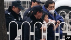 Cảnh sát đẩy một người biểu tình ủng hộ luật sư Phố Chí Cường ra khỏi khu vực tòa án ở Bắc Kinh.