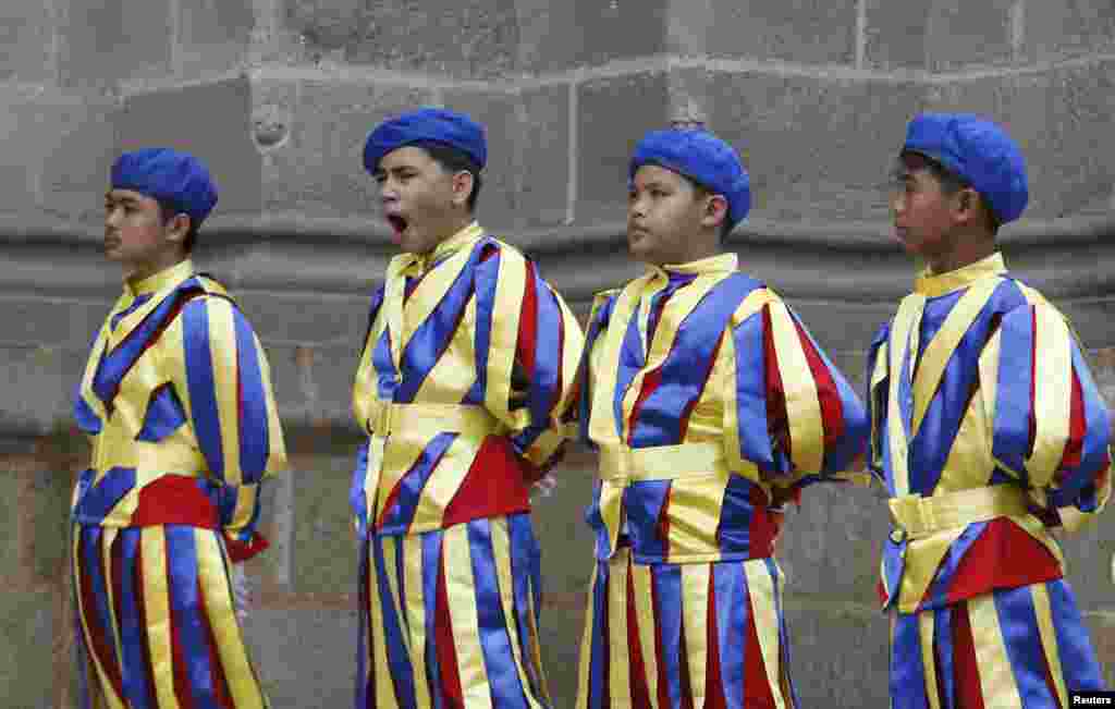 A boy yawns as schoolchildren dressed as Vatican Swiss guards rehearse outside the Manila Cathedral for the upcoming visit of Pope Francis in Manila, Philippines.