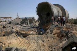 Trabajadores palestinos inspeccionan el daño en un centro municipal de distribución de agua después de un ataque aéreo israelí, en Mughraqa, en el centro de la Franja de Gaza, el jueves 9 de agosto de 2018.