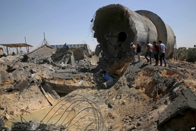 Trabajadores palestinos inspeccionan el daño en un centro municipal de distribución de agua después de un ataque aéreo israelí, en Mughraqa, en el centro de la Franja de Gaza, el jueves 9 de agosto de 2018.