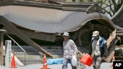 Evacuees walk past the historic Aso Shrine collapsed by powerful earthquakes in Aso, Kumamoto prefecture, Japan, April 17, 2016. 