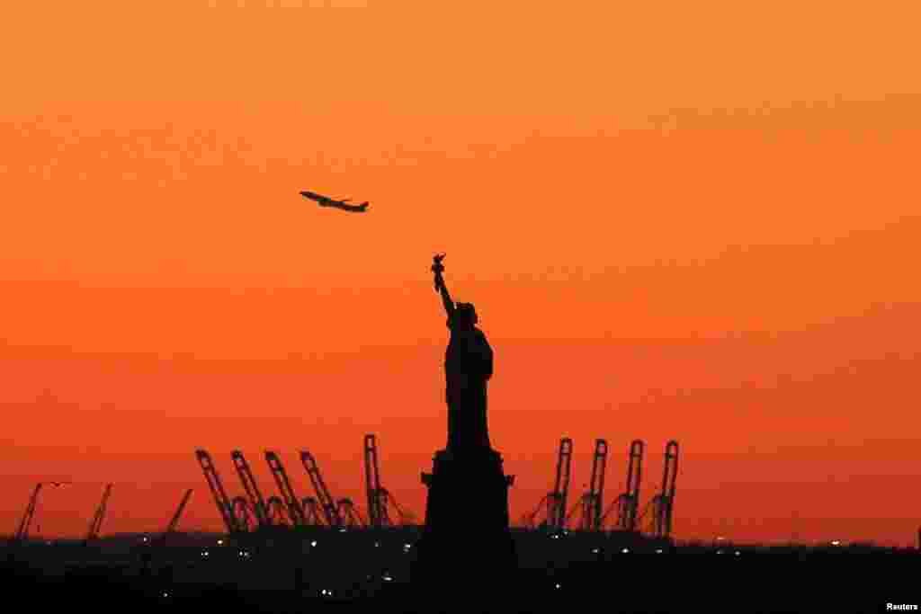 A plane is seen during take off in New Jersey behind the Statue of Liberty in New York&#39;s Harbor as seen from the Brooklyn borough, Feb. 20, 2016.