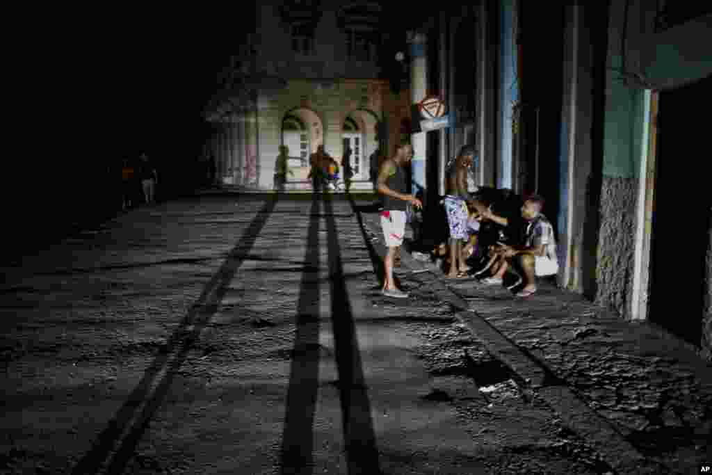 People sit on the sidewalk of a dark street after the electricity was cut off by the passage of Hurricane Irma in Havana, Cuba, Sept. 10, 2017.