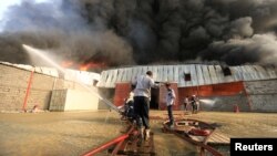 A crew battles a fire engulfing a warehouse of the World Food Program in Hodeida, Yemen, March 31, 2018.