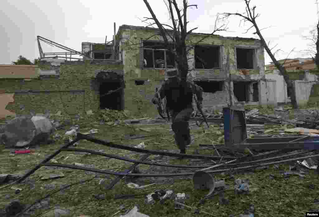 An Afghan police officer runs for cover after shootings and explosions in Kabul, May 24, 2013.