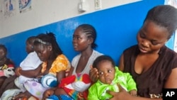 In this photo taken on Monday, Nov. 3, 2014, mothers wait inline for their children to be vaccinated by heath workers at the Pipeline Community Health Center, situated on the outskirts of Monrovia, Liberia. The Ebola outbreak has spawned a “silent killer,” experts say: hidden cases of malaria, pneumonia, typhoid and the like that are going untreated. (AP Photo/ Abbas Dulleh)