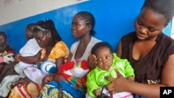 In this photo taken on Monday, Nov. 3, 2014, mothers wait inline for their children to be vaccinated by heath workers at the Pipeline Community Health Center, situated on the outskirts of Monrovia, Liberia. The Ebola outbreak has spawned a “silent kill