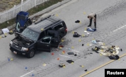 A law enforcement officer looks over the evidence near the remains of a SUV involved in the Wednesday's attack is shown in San Bernardino, California, Dec. 3, 2015.