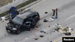 A law enforcement officer looks over the evidence near the remains of a SUV involved in the Wednesdays attack is shown in San Bernardino, California, Dec. 3, 2015. 