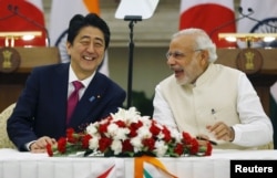 ນາຍົກລັດຖະມົນຕີ ຍີ່ປຸ່ນ ທ່ານ Shinzo Abe, ຊ້າຍ, ແລະຄູ່ຕຳແໜ່ງຂອງທ່ານ ຝ່າຍອິນເດຍ, ທ່ານ Narendra Modi, ສົນທະນາກັນຢ່າງສະໜິດສະໜົມ ໃນລະຫວ່າງ ການເຈລະຈາ ຂໍ້ຕົກລົງຕ່າງໆ ຢູ່ທີ່ ສະພາ Hyderabad ໃນນະຄອນຫຼວງ New Delhi,ປະເທດອິເດຍ, ວັນທີ 12 ທັນວາ 2015.