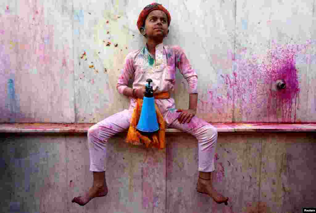 A boy holds a bottle as he takes part in the religious festival of Holi inside a temple in Nandgaon village, in the state of Uttar Pradesh, India.