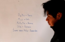 Jose Choque stands next to his work that he wrote on a dry erase board during a Uru language lesson, in a classroom in the Urus del Lago Poopo indigenous community, in Punaca, Bolivia, Monday, May 24, 2021.