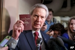 Rep. Walter B. Jones holds up a copy of the Constitution while talking to reporters as House Republicans emerge from a closed-door meeting on how to deal with the impasse over the Homeland Security budget, Feb. 26, 2015.