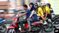 An Acehnese woman straddles on a motorbike on a road in Lhokseumawe, Aceh province, Indonesia. (AP Photo/Rahmat Yahya)