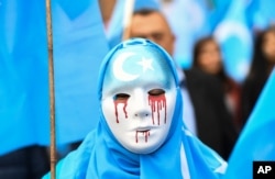 In Brussels on April 27, 2018, a person wearing a white mask with tears of blood takes part in a protest march of ethnic Uyghurs asking for the European Union to call upon China to respect human rights in the Chinese Xinjiang region.