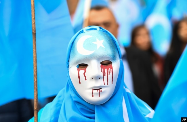 In Brussels on April 27, 2018, a person wearing a white mask with tears of blood takes part in a protest march of ethnic Uighurs asking for the European Union to call upon China to respect human rights in the Chinese Xinjiang region.