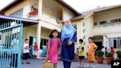 A Malaysian mother picks her daughter up from a pre-school after it was closed in Kuching, the capital of Malaysia's Borneo state of Sarawak. (File Photo)