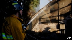 A firefighter works on a house destroyed by a wildfire called the Getty Fire in Los Angeles, Monday, Oct. 28, 2019. (AP Photo/Ringo H.W. Chiu)