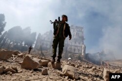 Houthi rebel fighters inspect the damage after a reported airstrike carried out by the Saudi-led coalition targeted the presidential palace in the Yemeni capital Sana'a, Dec. 5, 2017.