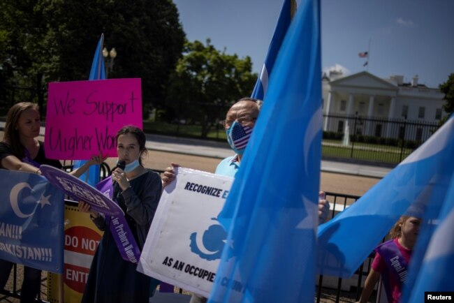 FILE - Activists hold a rally to protest the treatment of Uyghur women and to call for the Biden administration to boycott the 2022 Winter Olympics in Beijing, outside of the White House in Washington, May 27, 2021.