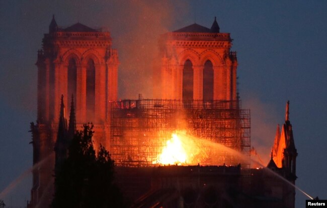 Fire fighters douse flames of the burning Notre Dame Cathedral in Paris, April 15, 2019.