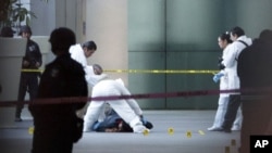 A forensic team inspects a body at Mexico City's International Airport Terminal 2, June 25, 2012.