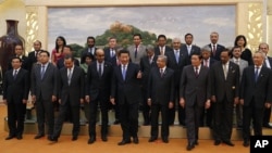 FILE - Chinese President Xi Jinping, center, shows the way to the guests who attended the signing ceremony of the Asian Infrastructure Investment Bank at the Great Hall of the People in Beijing, Oct. 24, 2014.