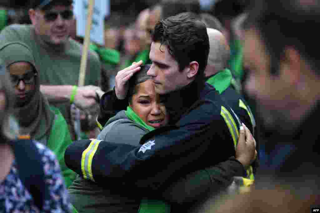 A woman hugs a fire-fighter as members of the public take part in a silent march as part of commemorations on the first anniversary of the Grenfell fire in west London on June 14, 2018.