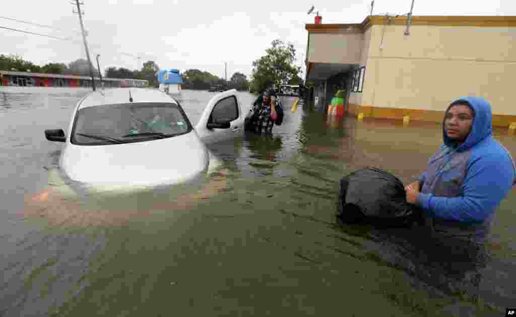 Conception Casa, center, and his friend Jose Martinez, right, check on Rhonda Worthington after her car become stuck in rising floodwaters from Tropical Storm Harvey in Houston, Texas, Monday, Aug. 28, 2017. The two men were evacuating their home that had become flooded when they encountered Worthington&#39;s car floating off the road. (AP Photo/LM Otero)