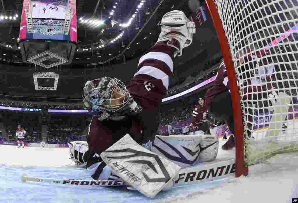 Latvia goaltender Edgars Masalskis reaches to block a shot on goal by the Czech Republic in the third period of a men's ice hockey game at the 2014 Winter Olympics, Feb. 14, 2014.