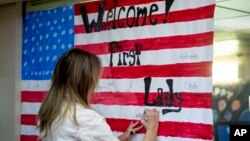 Ibu negara AS Melania Trump menandatangani bendera AS yang menyambut kedatangannya di Pusat Penahanan Ana-anak para migran di McAllen, Texas, Kamis (21/6). 
