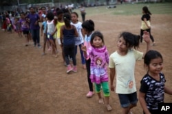 Children wait to receive gifts after a show to entertain them at the sports club where Central American migrants traveling with the annual Stations of the Cross caravan have been camped out in Matias Romero, Mexico, April 4, 2018.