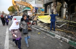 지난 11월 이란 테헤란에서 반정부 시위 중 화재가 발생한 은행 옆을 시민들이 지나고 있다.