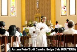 Seorang asisten pastor melayani jemaah saat misa Minggu di sebuah gereja di tengah pandemi COVID di Banyuwangi, Jawa Timur, 14 Juni 2020. (Foto: Antara/Budi Candra Setya via Reuters)