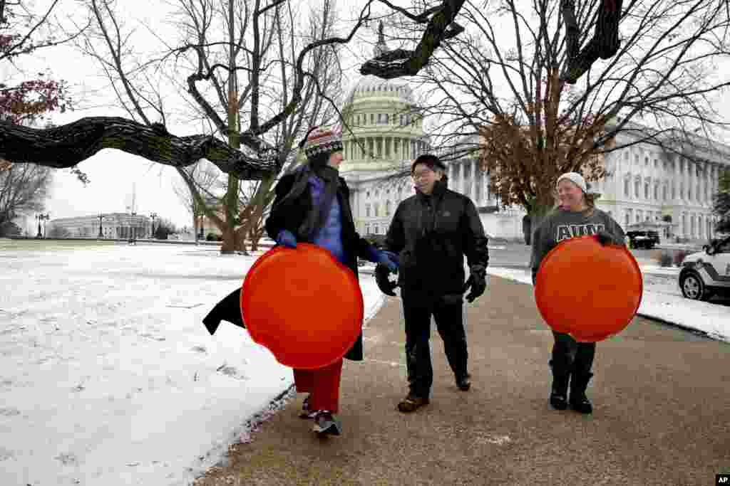 Jessica Pate, Sherri Sheu et Anna Foresee, qui vivent toutes dans le quartier de Capitol Hill à Washington, transportent des traîneaux devant le Capitole à Washington, le jeudi 4 janvier 2018.