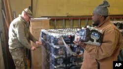 Staff Sgt. William Phillips, with the Michigan National Guard, assists a resident at a water distribution center Wednesday, Jan. 13, 2016, at a fire station in Flint, Michigan.