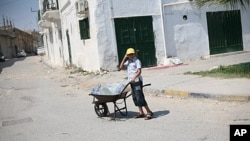 A Libyan boy carries water in a wheel barrow in Tripoli. Water has been cut off throughout the city, August 26, 2011