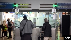 FILE - Travellers shows their documents to a border police officer at the immigration desk of Roissy Charles-de-Gaulle international airport, Feb. 1, 2021, 