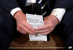 President Donald Trump holds notes during a listening session with students and teachers from Marjory Stoneman Douglas High School in Parkland, Florida, in the White House, Feb. 21, 2018.