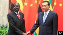 Zimbabwean President Robert Mugabe, left, and Chinese Premier Li Keqiang pose for photographers prior to their meeting at the Great Hall of the People in Beijing, Aug. 26, 2014. 