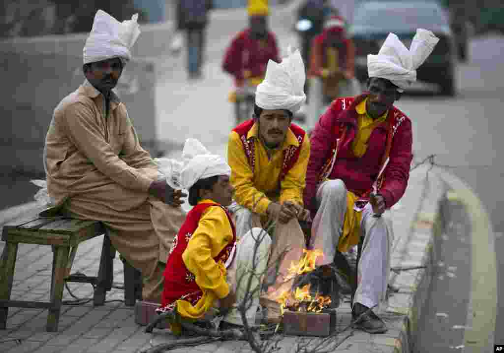 Pakistani street performers sit around a fire waiting for customers on a chilly evening in Rawalpindi.