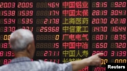 FILE - An investor looks at information displayed on an electronic screen at a brokerage house in Shanghai, China, June 30, 2015. 