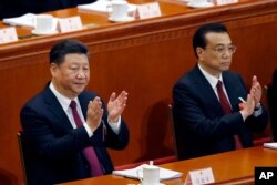 FILE - Chinese President Xi Jinping, left, and Chinese Premier Li Keqiang applaud during the opening session of the annual National People's Congress at the Great Hall of the People in Beijing, March 5, 2018.