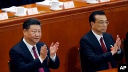 Chinese President Xi Jinping, left, and Chinese Premier Li Keqiang applaud during the opening session of the annual National People's Congress at the Great Hall of the People in Beijing, March 5, 2018.