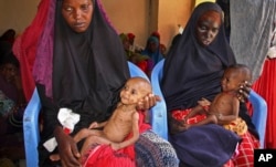 FILE - Malnourished babies are held by their mothers, both of whom fled the drought in southern Somalia, at a feeding center in a camp in Mogadishu, Somalia, Feb. 25, 2017.