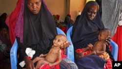 Malnourished babies are held by their mothers, both of whom fled the drought in southern Somalia, at a feeding center in a camp in Mogadishu, Somalia, Feb. 25, 2017.