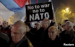 FILE - A demonstrator holds a sign during an anti-NATO protest in Podgorica, Montenegro, Dec. 12, 2015.
