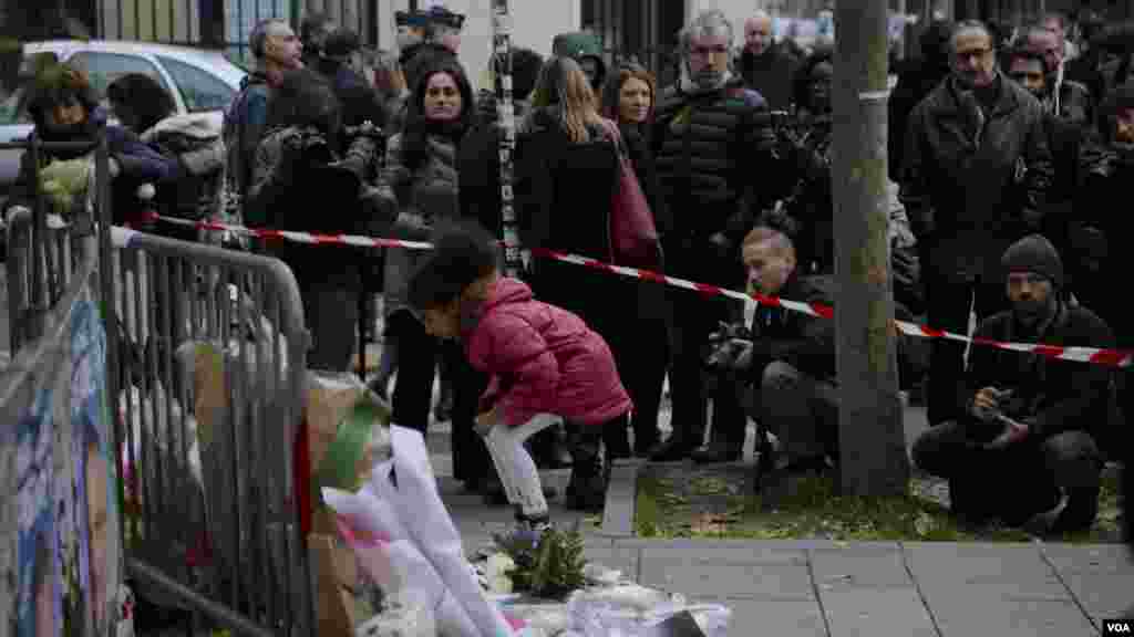 A small girl lays flowers as part of a memorial to victims a day after more than 120 people were killed in a series of attacks in Paris, Nov. 14, 2015.