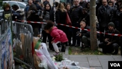 A girl lays flowers as part of a memorial to victims of the terror attacks in Paris, France, Nov. 14, 2015.